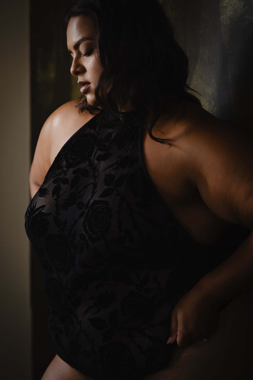 A woman in a black floral halter outfit looking towards the studio window