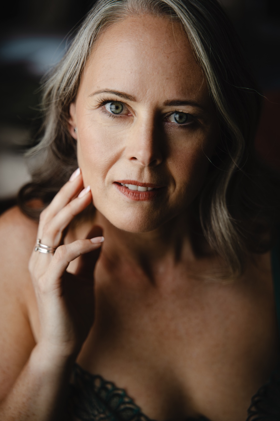 A woman looking towards the camera with her hand gently resting beside her face