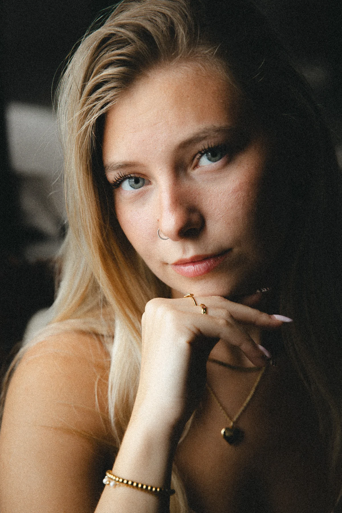 A softly lit portrait of a woman resting her chin on her hand